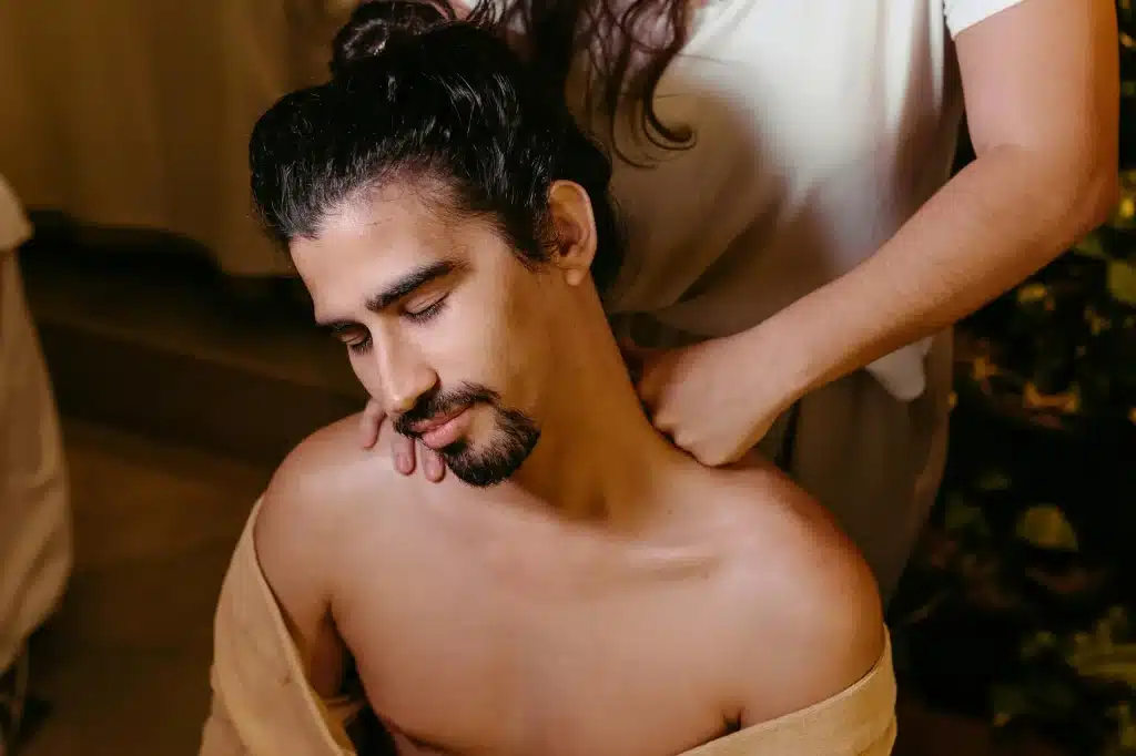 A person receives a soothing neck massage, wrapped in a beige cloth, in a cozy at Well in Montclair for Emsella in Montclair, NJ.