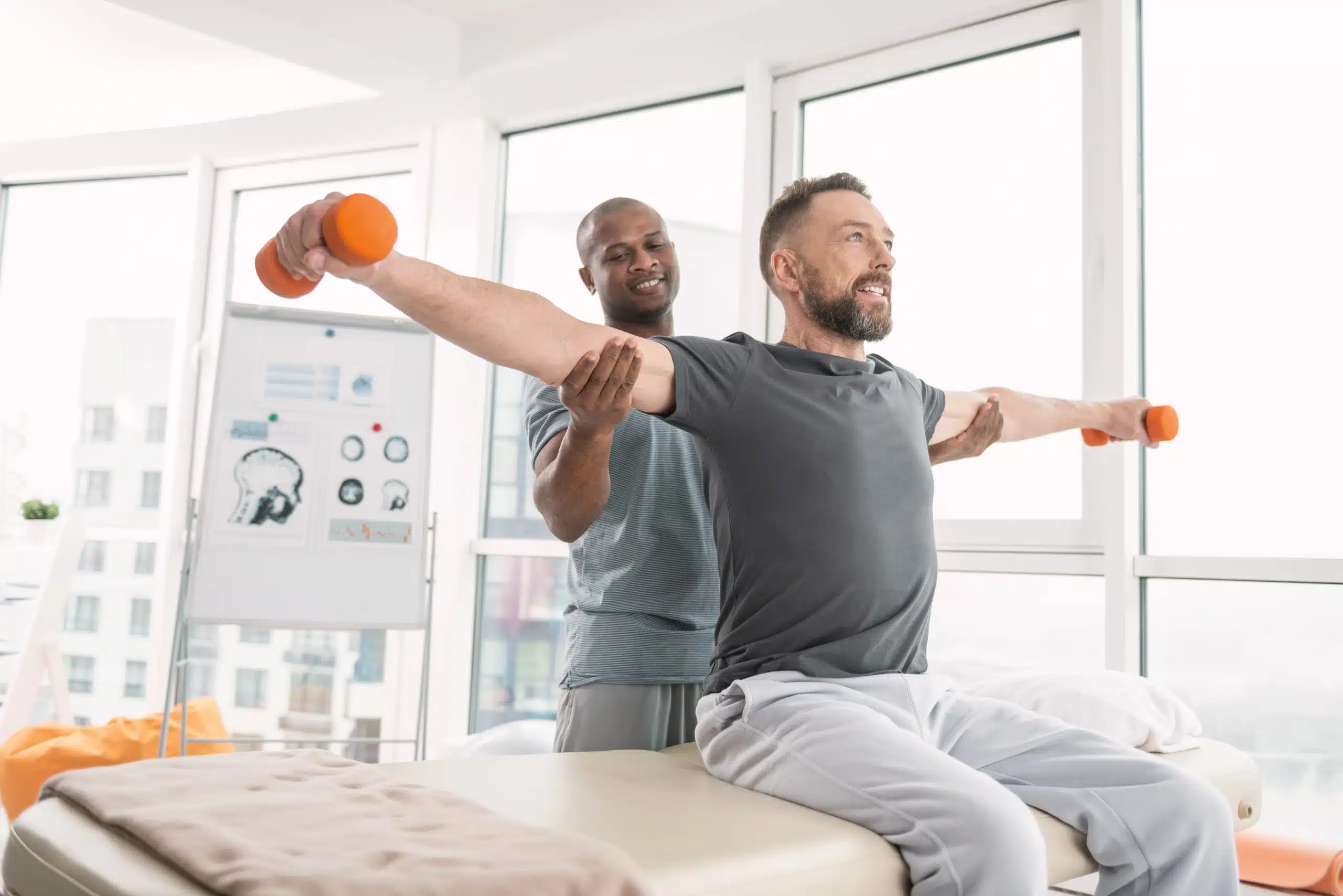 Nice positive doctor standing behind his patient while giving him Physical Therapy at Well in Montclair in Montclair, NJ.