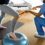 Physical therapist in Montclair, NJ assisting a patient with balance and strength training using a resistance band and stability equipment during rehabilitation.